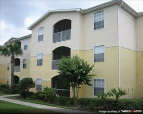 Oviedo apartment for rent - a yellow building with palm trees and a sidewalk