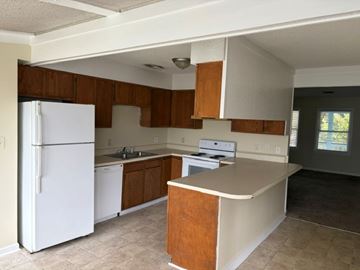 Beaufort - Available Now - Special apartment for rent - A kitchen with a white refrigerator and wooden cabinets.