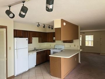 Beaufort - Coming Available 8/21/26 apartment for rent - A kitchen with brown cabinets and a white fridge.