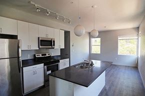Oklahoma City apartment for rent - an empty kitchen with white cabinets and black counter tops