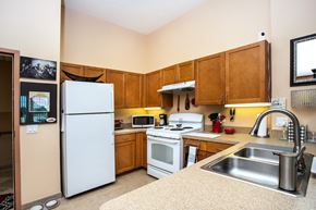 Fort Myers apartment for rent - kitchen with stainless steel sink, white appliances, and wood cabinets