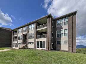Scranton apartment for rent - a brick apartment building with green grass and a blue sky