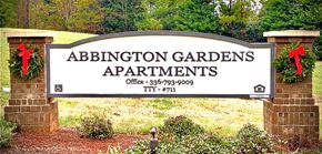 Winston-Salem apartment for rent - A sign for Abbington Gardens Apartments is displayed in front of a green area.