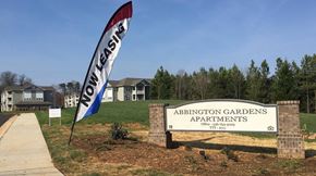 Winston-Salem apartment for rent - a sign for adoption gardens apartments in front of a field with trees