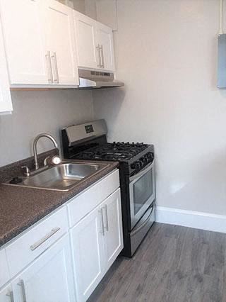Washington apartment for rent - A kitchen with a black stove top oven and white cabinets.