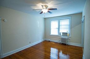 Washington apartment for rent - A room with a ceiling fan and a window with a radiator beneath it.