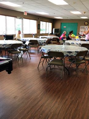 Homestead apartment for rent - tables and chairs beside large windows in community room at Deedco Gardens