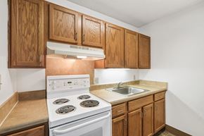 Jacksonville apartment for rent - residential kitchen at Sundale Manor Apartments with white appliances and wood cabinetry