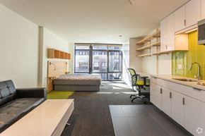 Ithaca apartment for rent - A modern office space with a black leather sofa, a green chair, and a kitchenette.