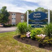 Stoughton apartment for rent - the sign with flowers in front of the building