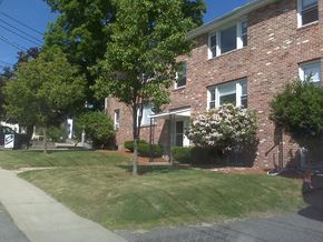 Milford apartment for rent - the front of a brick apartment building with a lawn and trees