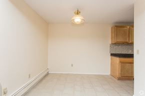 Milford apartment for rent - an empty living room with a kitchen with cabinets and a ceiling lamp