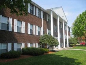 Milford apartment for rent - a brick apartment building with green grass and trees