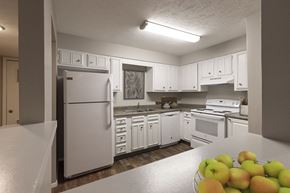 Omaha apartment for rent - a kitchen with white cabinets and appliances and a bowl of fruit