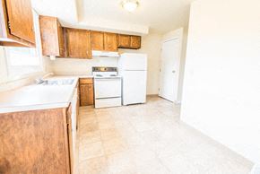 Amherst triplex for rent - a kitchen with white appliances and wooden cabinets