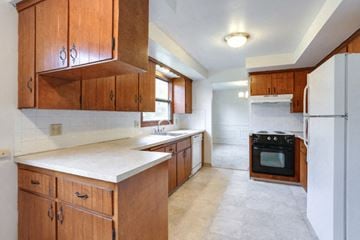 Williamsville house for rent - a kitchen with wooden cabinets and a stove and a refrigerator