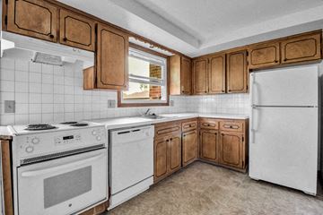 Williamsville triplex for rent - a kitchen with white appliances and wooden cabinets