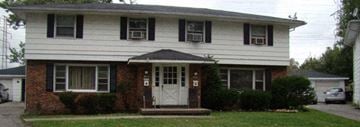 Tonawanda triplex for rent - A white house with a black roof and a white door.