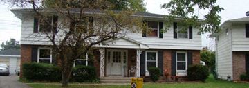 Tonawanda triplex for rent - A white house with a tree in front.