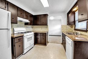Tonawanda house for rent - a kitchen with white appliances and brown cabinets