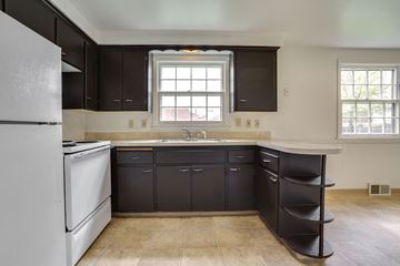 Tonawanda house for rent - A kitchen with black cabinets and a white refrigerator.