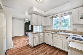 Amherst house for rent - an empty kitchen with white cabinets and a window