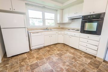 Amherst house for rent - A kitchen with white appliances and brown tiled floors.