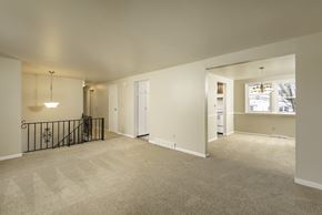 Amherst house for rent - A spacious room with a carpeted floor and a black metal railing.