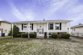 Amherst house for rent - A white house with a front yard and a blue trash bin.