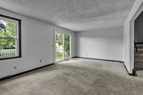 Amherst triplex for rent - A room with a carpeted floor and a window with a view of a fence and trees.