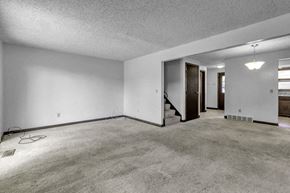 Amherst triplex for rent - A room with a carpeted floor and a staircase.