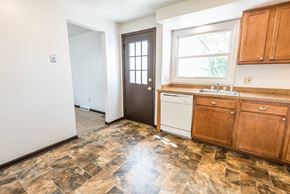Amherst triplex for rent - a kitchen with wooden cabinets and a sink and a door
