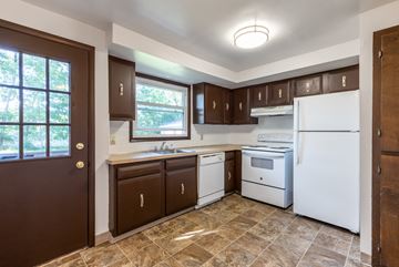 Amherst triplex for rent - an empty kitchen with white appliances and brown cabinets