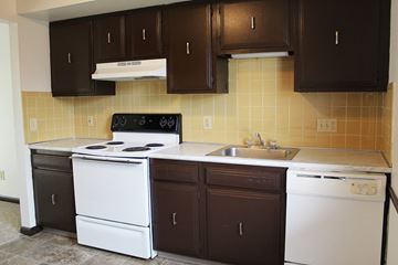 Amherst triplex for rent - an empty kitchen with white appliances and brown cabinets