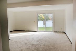 Amherst triplex for rent - an empty living room with a white carpet and a glass door