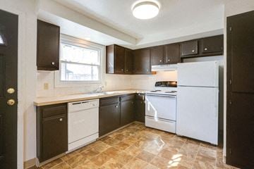 Amherst triplex for rent - A kitchen with brown cabinets and a white refrigerator.