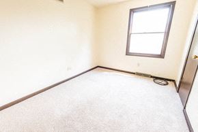 Amherst triplex for rent - A room with a carpeted floor, a window, and a door.