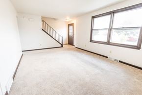 Amherst triplex for rent - the living room and dining room of an empty home with large windows and carpeting