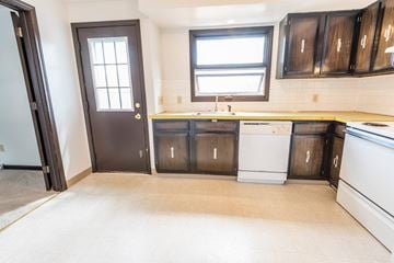 Amherst triplex for rent - a kitchen with wooden cabinets and a white dishwasher