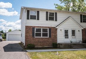 Amherst triplex for rent - the front of a white house with a garage and a driveway