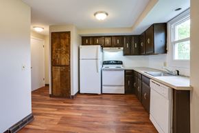 Amherst triplex for rent - an empty kitchen with white appliances and dark cabinets
