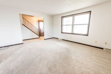 Amherst triplex for rent - the living room and dining room of a house with carpet and a large window