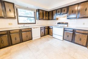 Amherst triplex for rent - a kitchen with wooden cabinets and white appliances