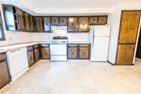 Amherst triplex for rent - an empty kitchen with white appliances and wooden cabinets
