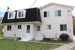 Amherst triplex for rent - A two-story house with a white front door and a black roof.