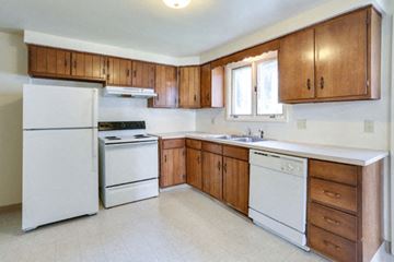 Amherst triplex for rent - A kitchen with white appliances and wooden cabinets.
