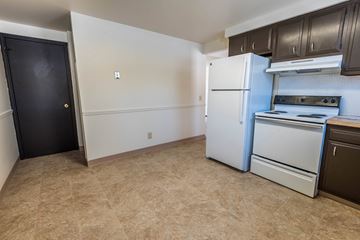Amherst triplex for rent - A kitchen with a white refrigerator, black door, and brown cabinets.