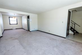 Amherst triplex for rent - A spacious room with a window and a staircase.