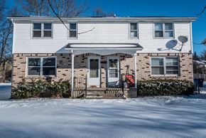 Amherst triplex for rent - A house with a white front porch and a red mailbox sits in the snow.