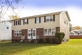 Amherst triplex for rent - a white and brick house with a green lawn